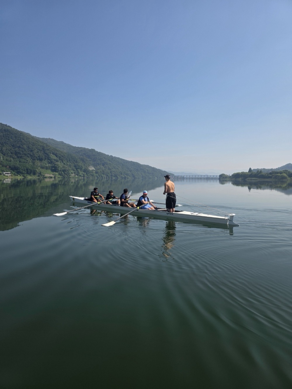 A coach guiding a crew on a calm lake